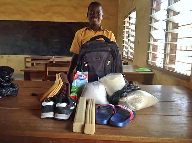 Student standing in a classroom with school supplies and learning materials.