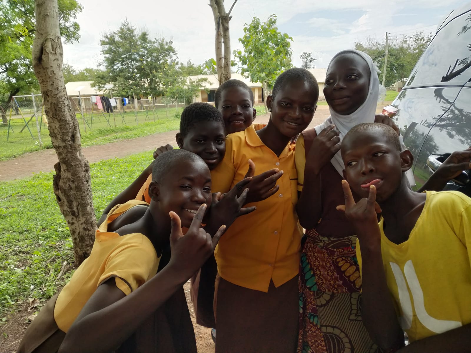 Students smiling together outdoors after receiving school supplies.